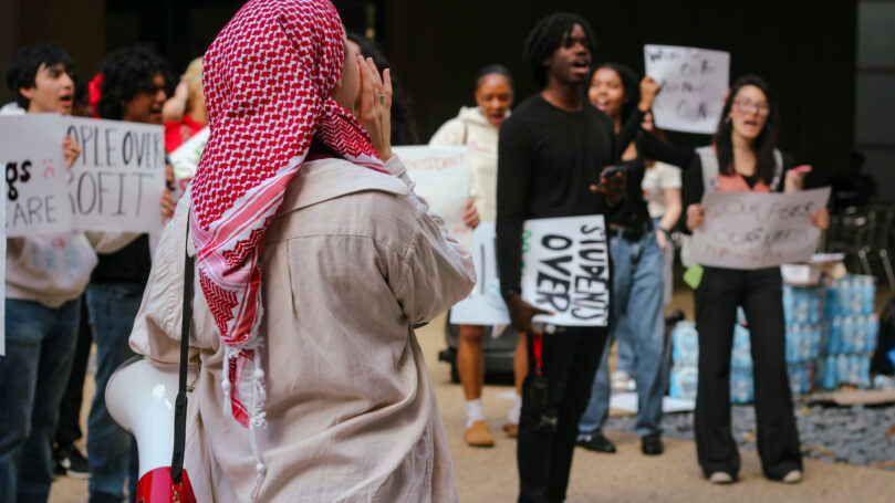 Young person wearing a keffiyeh and bullhorn.