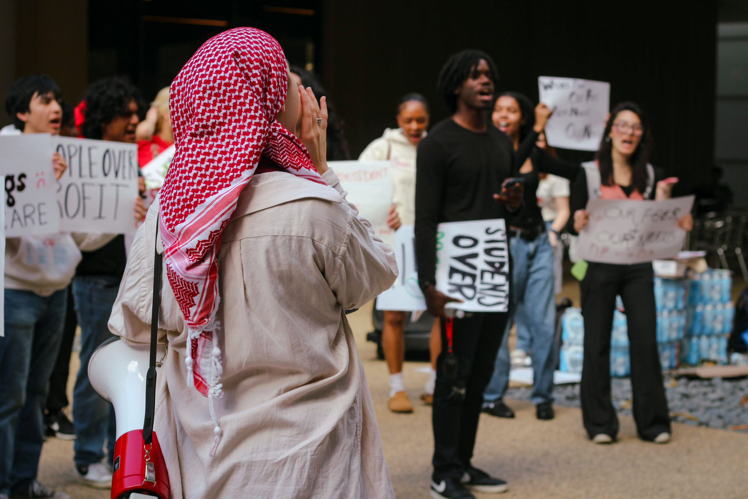 Young person wearing a keffiyeh and bullhorn.
